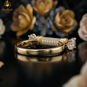 "Angled view of a custom gold ring showing a smooth gold band that transitions into a horizontal, pave-set cylindrical centerpiece with clear stones on the ends."
