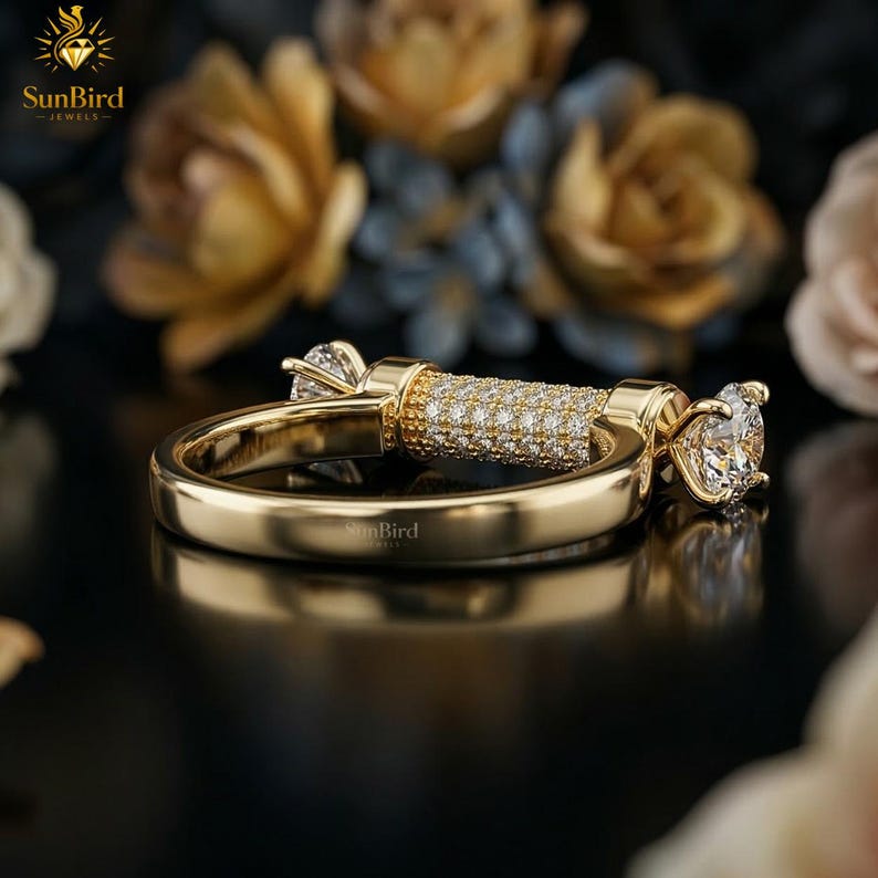 "Angled view of a custom gold ring showing a smooth gold band that transitions into a horizontal, pave-set cylindrical centerpiece with clear stones on the ends."