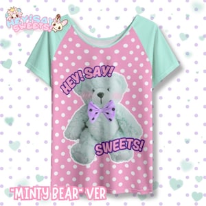 May include: A short-sleeved t-shirt with a mint green and pink polka dot design. The shirt features a light blue teddy bear with a purple bow tie and the text "HEY! SAY! SWEETS!". The words "MINTY BEAR" VER are at the bottom.