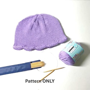 Può includere: Un cappello lavorato a maglia lilla con bordo smerlato, un gomitolo di lana, ferri da maglia e la scritta "Pattern ONLY" su sfondo bianco. Il cappello è probabilmente fatto a mano.