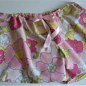 Op de afbeelding: Roze en gele pyjamabroek met bloemenprint en een roze satijnen strik aan de taille.
