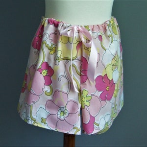 Op de afbeelding: Roze en gele pyjamabroek met bloemenprint en een satijnen strikband in de taille.