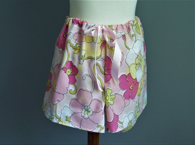 Op de afbeelding: Roze en gele pyjamabroek met bloemenprint en een satijnen strikband in de taille.