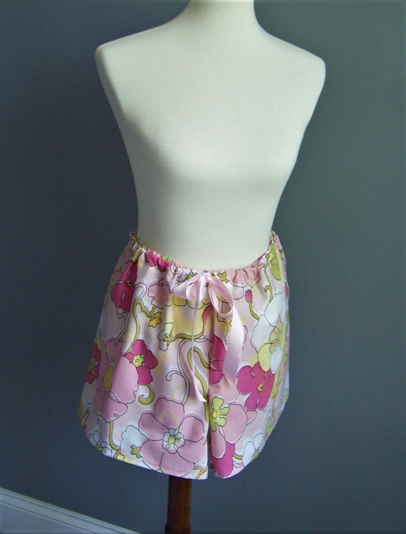 Op de afbeelding: Een roze en witte bloemenprint rok met een satijnen lint strik. De rok heeft een retro stijl uit de jaren 1970.