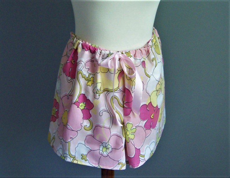 Op de afbeelding: Een roze en witte rok met bloemenprint en een satijnen strikband aan de taille.