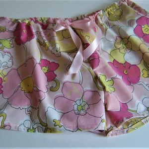 Op de afbeelding: Roze pyjamabroek met bloemenprint en een roze satijnen strikband in de taille.