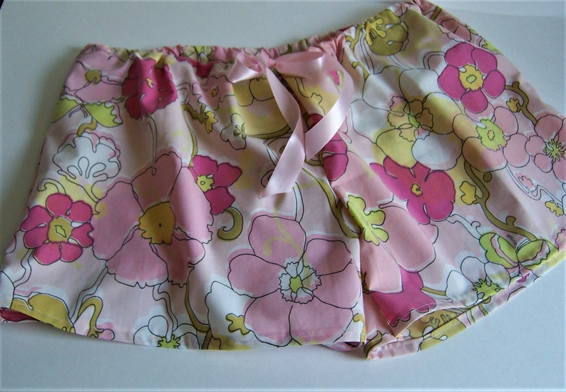 Op de afbeelding: Roze pyjamabroek met bloemenprint en een roze satijnen strikband in de taille.