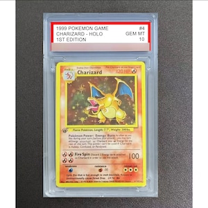 May include: A 1999 1st Edition Charizard holographic trading card encased in a clear protective slab. The label reads 1999 POKEMON GAME CHARIZARD - HOLO 1ST EDITION GEM MT 10. The card features a yellow border, fire-type graphics, and text.
