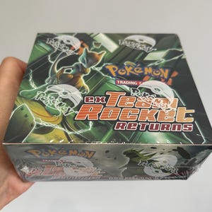 May include: A sealed Pokémon ex Team Rocket Returns trading card game booster box. The box features dark green and black graphics with an illustration of Mewtwo, the Pokémon logo, and the text ex Team Rocket Returns in orange and white lettering.