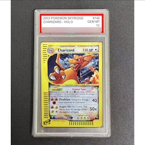 May include: A graded Pokémon card featuring Charizard from the 2003 Skyridge set. The card is in a protective case and has a GEM MT 10 grade. The card's artwork depicts Charizard in a dynamic pose with a yellow and orange color scheme.