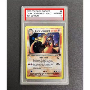 Może przedstawiać: Karta Pokémon z oceną Dark Charizard. Karta pochodzi z zestawu 2000 Pokémon Rocket, 1st Edition i ma ocenę GEM MT 10. Grafika karty przedstawia ognistego Charizarda. Karta ma 170 cm długości i waży 90 kg.