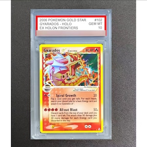 May include: A 2006 Pokemon Gold Star Gyarados Holo trading card from the EX Holon Frontiers set, graded GEM MT 10. The card features a red Gyarados illustration, 80 HP, and the attacks Spiral Growth and All-out Blast, all encased in a clear slab.