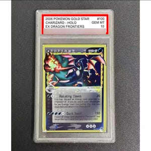 May include: A graded Pokémon card featuring Charizard from the 2006 Gold Star series. The card is in a protective case and has the text "2006 POKEMON GOLD STAR CHARIZARD - HOLO EX DRAGON FRONTIERS #100 GEM MT 10". The card art depicts Charizard in a dynamic pose.