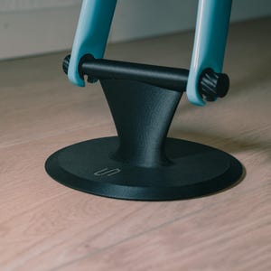 May include: A black and light blue stand with a circular base and a curved support. The stand has a cylindrical bar held in place by two light blue supports. The base has a small, stylized 'S' etched into it.