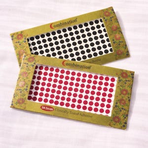 May include: Two packages of adhesive dots. One with black dots on white, the other with red dots on white. The packages have a floral design and the text "Combination" and "24 Seven Clinically Tested Adhesive".