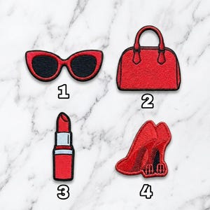 May include: Set of four red embroidered patches featuring fashion accessories. Includes cat-eye sunglasses, a handbag, lipstick, and high heels. Each patch is outlined in black and numbered 1 through 4.