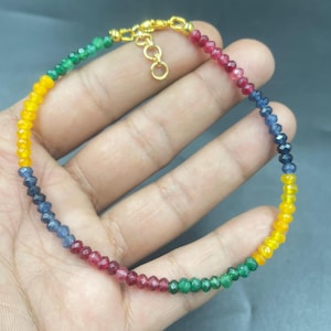 Op de afbeelding: Een veelkleurige kralenarmband met een gouden sluiting. De armband toont een regenboog aan kleuren, waaronder geel, groen, blauw en rood. De kleine, facetgeslepen kralen creëren een sprankelend effect. Een delicaat sieraad.