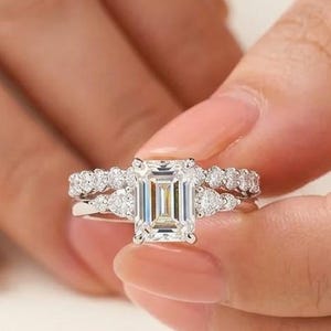 Anillo de compromiso de tres piedras con talla esmeralda y alianza de boda con engaste de burbuja curvado, conjunto nupcial de oro blanco macizo con halo oculto y piedras laterales en forma de pera.