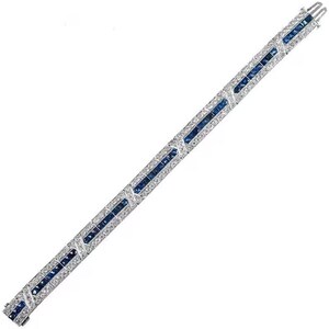 May include: A silver-toned metal bracelet featuring a central row of square-cut blue sapphires flanked by two rows of small, round, clear white stones. The design includes repeating X-shaped metal links set with clear stones between the sapphire segments.
