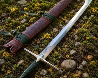 Puede incluir: Una espada plateada con hoja curva y empuñadura verde texturizada con un pomo circular. A su lado yace una vaina de cuero marrón con intrincados patrones florales en relieve, asegurada por correas de cuero verde y hebillas de latón.