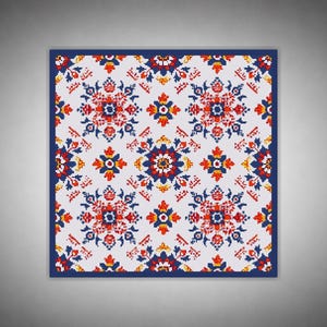 Könnte beinhalten: Quadratischer Stoff mit einem sich wiederholenden Blumenmuster in Rot, Blau und Gelb auf weißem Hintergrund. Das Design zeigt symmetrische Blumenmotive mit einem dunkelblauen Rand. Die Ästhetik erinnert an traditionelle Volkskunst.