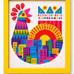 Puede incluir: Una colorida obra de arte de punto de cruz en un marco amarillo. El diseño presenta un gallo con un horizonte de la ciudad, un sol y una corona. El gallo está compuesto por varios colores, incluyendo rosa, azul, amarillo y verde. El horizonte de la ciudad es una mezcla de edificios azules, rosas y amarillos.