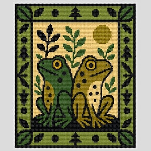 May include: A cross-stitch pattern featuring two frogs sitting back-to-back on a dark ground against a cream background. The frogs are green and olive with yellow eyes. The design includes leafy sprigs, a circular sun, and a decorative border.