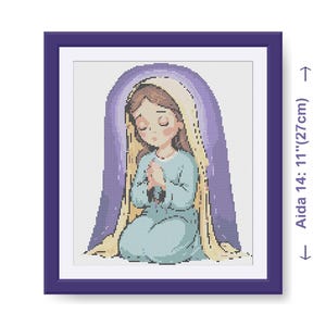 May include: A framed cross-stitch artwork depicting a kneeling figure with hands clasped in prayer. The figure wears a light blue dress and head covering, against a purple and yellow backdrop. The frame is purple, and the Aida cloth measures 27cm.