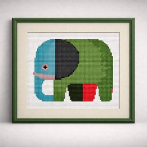 May include: A framed cross-stitch art piece featuring a stylized elephant. The elephant is primarily green with a blue head, black ear, and red and black accents. The artwork is framed in a green wooden frame.