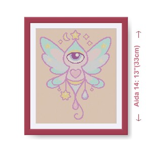 May include: Framed cross-stitch art featuring a whimsical winged creature with a large eye, heart, and star accents. The artwork is in a red frame, with dimensions of 14 inches by 13 inches.