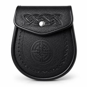 May include: Black leather sporran with Celtic knotwork and a decorative emblem. The sporran has a flap closure with a silver-colored button. The edges are stitched with a decorative pattern.