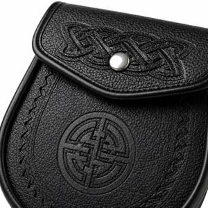 May include: Black leather sporran with embossed Celtic knot designs and a circular emblem. It has a flap closure with a silver button and decorative stitching. The leather has a textured finish. The sporran is a traditional Scottish accessory.