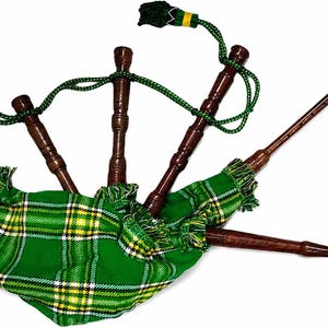 May include: A traditional bagpipe with a green and yellow plaid bag. The instrument features dark brown wooden pipes, green cords, and decorative tassels. Two reeds are also visible.