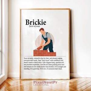 Könnte beinhalten: Ein gerahmter Druck mit dem Wort "Brickie" und einer Definition. Das Bild zeigt einen Maurer bei der Arbeit, der Ziegel legt. Der Text beschreibt die Arbeitsmoral des Maurers. Der Druck ist in einem Holzrahmen.