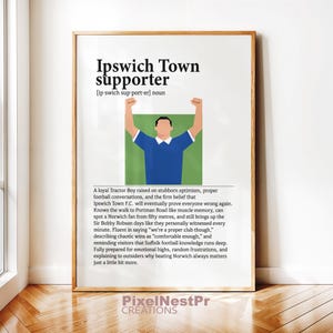 May include: Framed print with the text "Ipswich Town supporter" and a definition. The image includes a graphic of a person in a blue shirt with arms raised. The print also has a description of an Ipswich Town supporter.