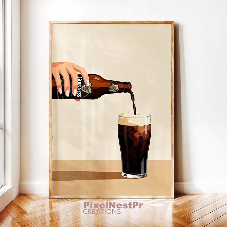 May include: A framed print depicts a hand pouring Guinness stout from a brown bottle into a pint glass. The beer is dark with a creamy white head. The Guinness label is visible on the bottle.