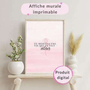 May include: A framed pink and white print with the text "TU MÉRITES UNE VIE QUI TE FAIT vibrer" and a rose illustration. The print is labeled "Affiche murale imprimable" and "Produit digital". Decorative flowers and vase are on a wooden shelf.