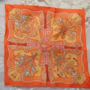 Orange patterned 1/6 doll scarf laid flat beside a gold-framed mirror