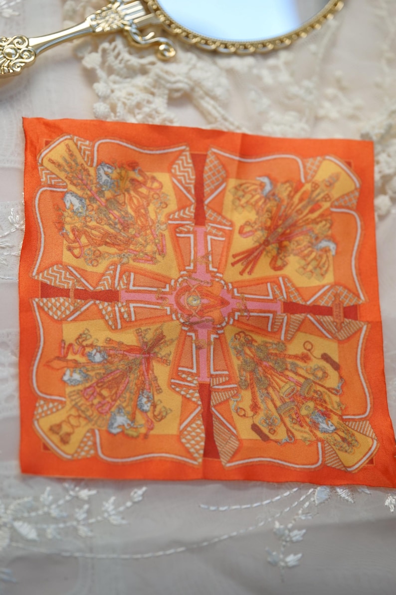 Orange patterned 1/6 doll scarf laid flat beside a gold-framed mirror