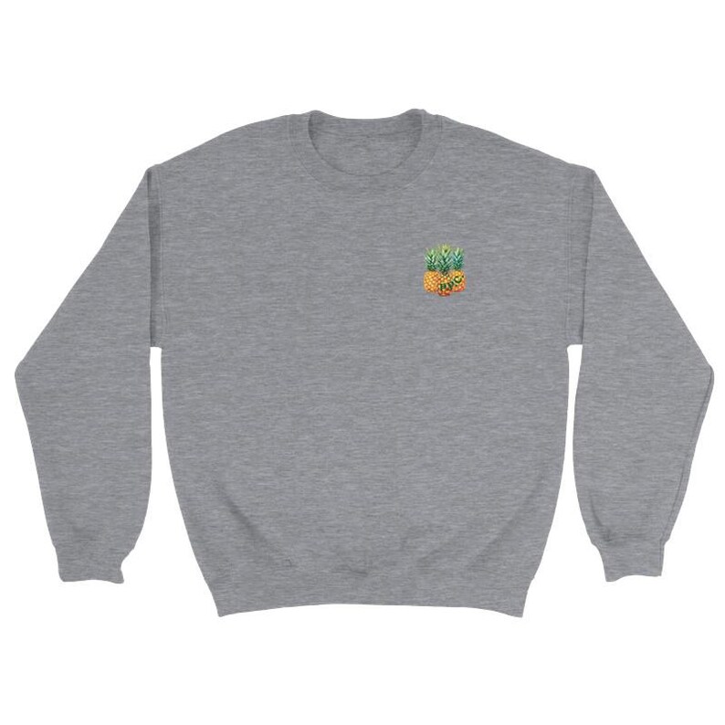 Puede incluir: Una sudadera gris jaspeado con un peque&ntilde;o dise&ntilde;o bordado de pi&ntilde;a en el pecho izquierdo. La pi&ntilde;a est&aacute; representada en tonos amarillos, naranjas y verdes. La sudadera tiene cuello redondo y mangas largas, ofreciendo un estilo casual.