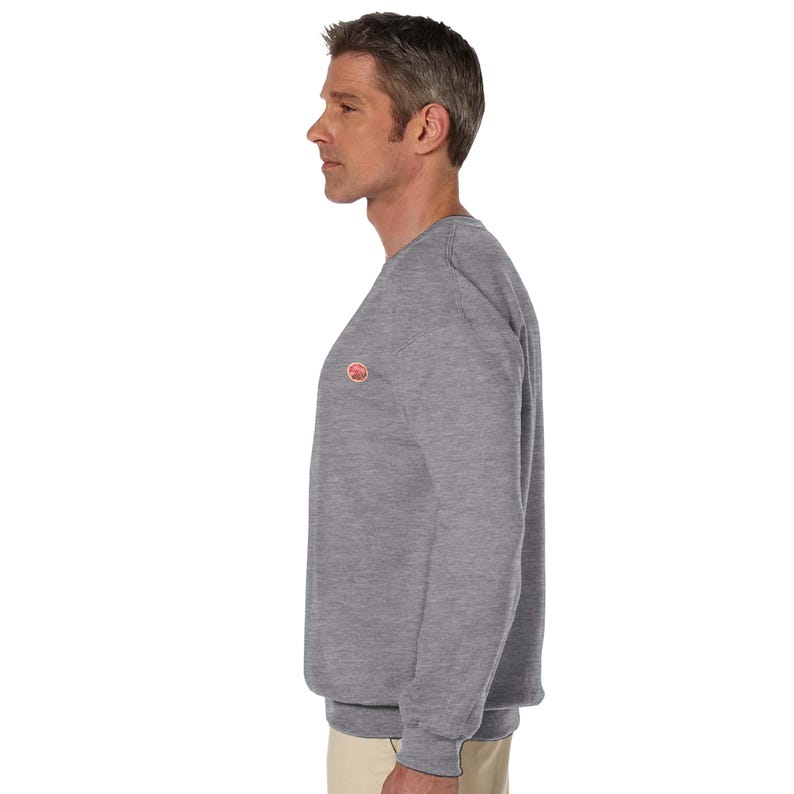 May include: A heather gray sweatshirt with a small, circular logo on the chest. The long-sleeved crew neck top is made of a soft material. The sweatshirt is a casual garment suitable for various activities.