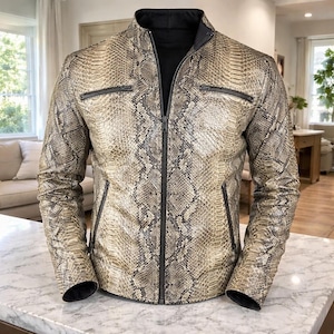 May include: A snakeskin-patterned jacket with a black collar and zipper. The jacket has two zippered chest pockets and two side pockets. The jacket is made of a light brown and grey material.