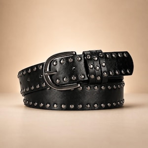 May include: A black belt featuring a smooth finish and two rows of evenly spaced, rounded silver-toned metal studs along the edges. The belt includes a matching silver-toned metal buckle and two loops, with a series of pre-punched holes for adjustment.