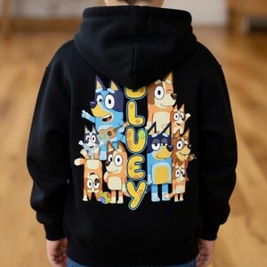 Puede incluir: Sudadera con capucha negra con un gr&aacute;fico colorido de perros de dibujos animados y la palabra "Bluey" en amarillo. El dise&ntilde;o incluye varios personajes de perros en diferentes poses. La sudadera est&aacute; hecha de un material suave y tiene una capucha.