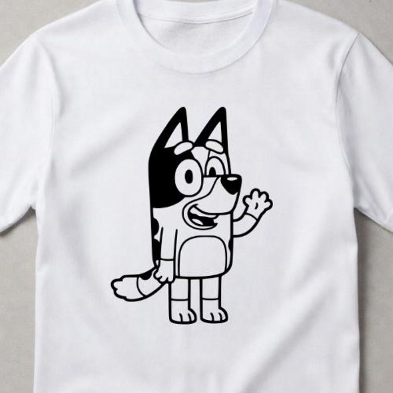 Puede incluir: Una camiseta blanca de manga corta con un gr&aacute;fico de l&iacute;neas en blanco y negro de un perro de dibujos animados de pie y saludando. El perro tiene orejas puntiagudas, un patr&oacute;n de manchas en el cuerpo y una cola grande, centrado en el pecho.