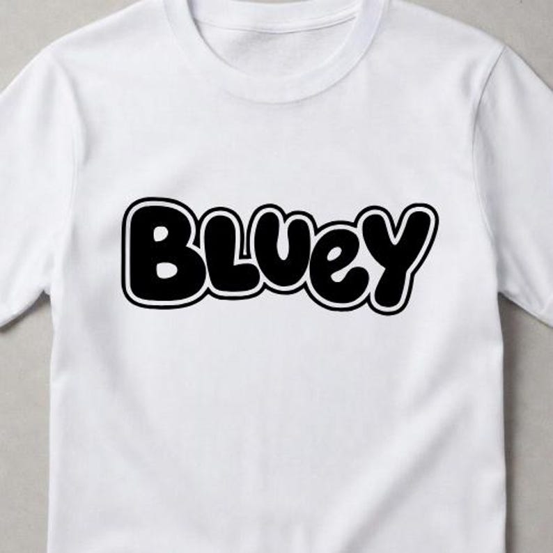 Puede incluir: Una camiseta blanca de manga corta con la palabra Bluey impresa en una fuente negra, negrita y redondeada de estilo burbuja en el centro del pecho. El texto tiene un contorno negro grueso y un borde interior blanco, creando un dise&ntilde;o gr&aacute;fico.