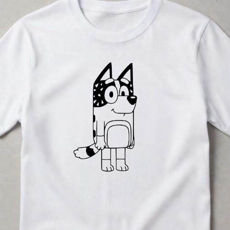 Puede incluir: Una camiseta blanca de manga corta con un gr&aacute;fico de l&iacute;neas negras de un personaje de perro de dibujos animados. El perro aparece de pie con una oreja estampada y una cola a rayas, centrado en la parte delantera de la camiseta con cuello redondo.
