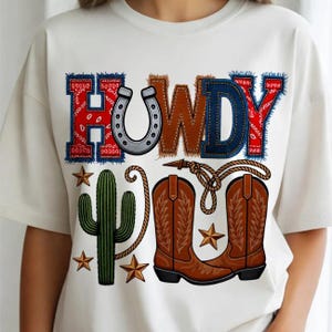Peut inclure: T-shirt blanc avec un motif sur le thème du western. Le mot "HOWDY" est affiché avec un fer à cheval, des bottes de cowboy, un cactus et des étoiles. Les lettres sont dans différentes textures et couleurs, dont le denim, l'imprimé bandana et le cuir marron.