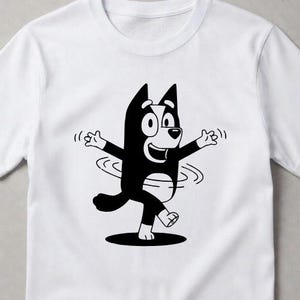 Puede incluir: Una camiseta blanca de manga corta con un estampado gr&aacute;fico en blanco y negro de un perro de dibujos animados con los brazos extendidos y un efecto de giro alrededor de la cintura. El personaje tiene orejas puntiagudas y una sonrisa.