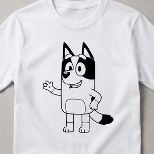 Puede incluir: Una camiseta blanca de manga corta con un gr&aacute;fico de l&iacute;neas negras de un perro de dibujos animados de pie y saludando. El personaje tiene orejas puntiagudas, un hocico redondeado y una cola tupida con manchas negras s&oacute;lidas en las orejas.